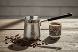 Turku kafijas kanna dzīvesstila fotogrāfijā ar kafijas pupiņām un tradicionālo turku kafijas tasi - autentiska kafijas rituāla atmosfēra